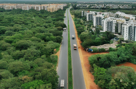Aerial view of Medavakkam to Mambakkam road where apartments and Premium Villas in Chennai seen along the road in a scenic background